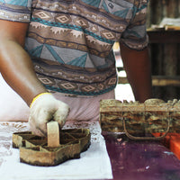 a photo of a batik artisan blocking a pattern for a batik shirt