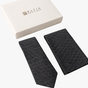 A black textured necktie and matching black pocket square set with a white Batik Boutique gift box on a clean white background.