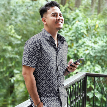 A lifestyle photo of a man wearing an authentic batik shirt made by malaysian artisans in the pattern grey arabesque