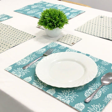 A lifestyle photo of turquoise pineapple homeware set containing 4 placemats and coasters setup on the table. 