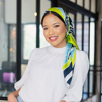 a lifestyle photo of a woman wearing batik scarf in kl skyline pattern in teal rimba from batik boutique