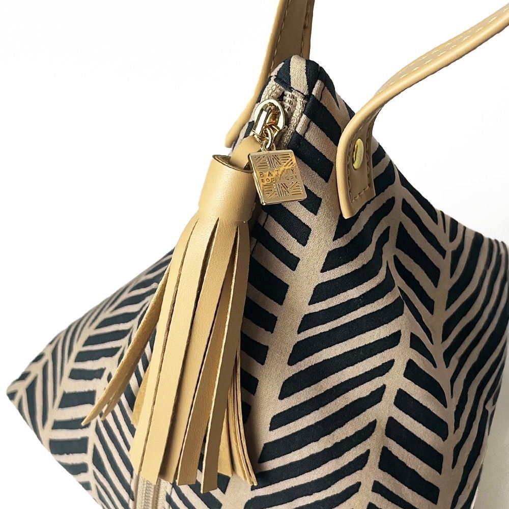 Close-up of Batik Boutique’s Ketupat Bag showcasing the Black Banana Leaf print, gold zipper, and signature charm.