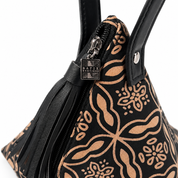 Close-up of a black handbag with a tan floral and paisley pattern, black leather handles, a black leather tassel zipper pull, and a silver-tone metal brand plaque reading 'MATIX BOUTIQUE'.