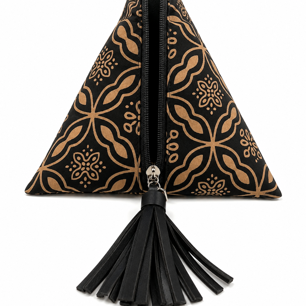 A black and tan patterned zippered clutch bag with a black tassel, shown against a plain white background.