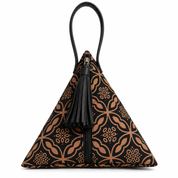 A small pyramid-shaped handbag with a black and tan geometric pattern, featuring a black leather top handle, zipper, and tassel detail, set against a plain white background.