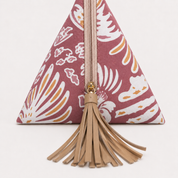 A maroon and gold patterned triangular clutch bag with a blonde leather tassel zipper pull, shown against a plain white background.