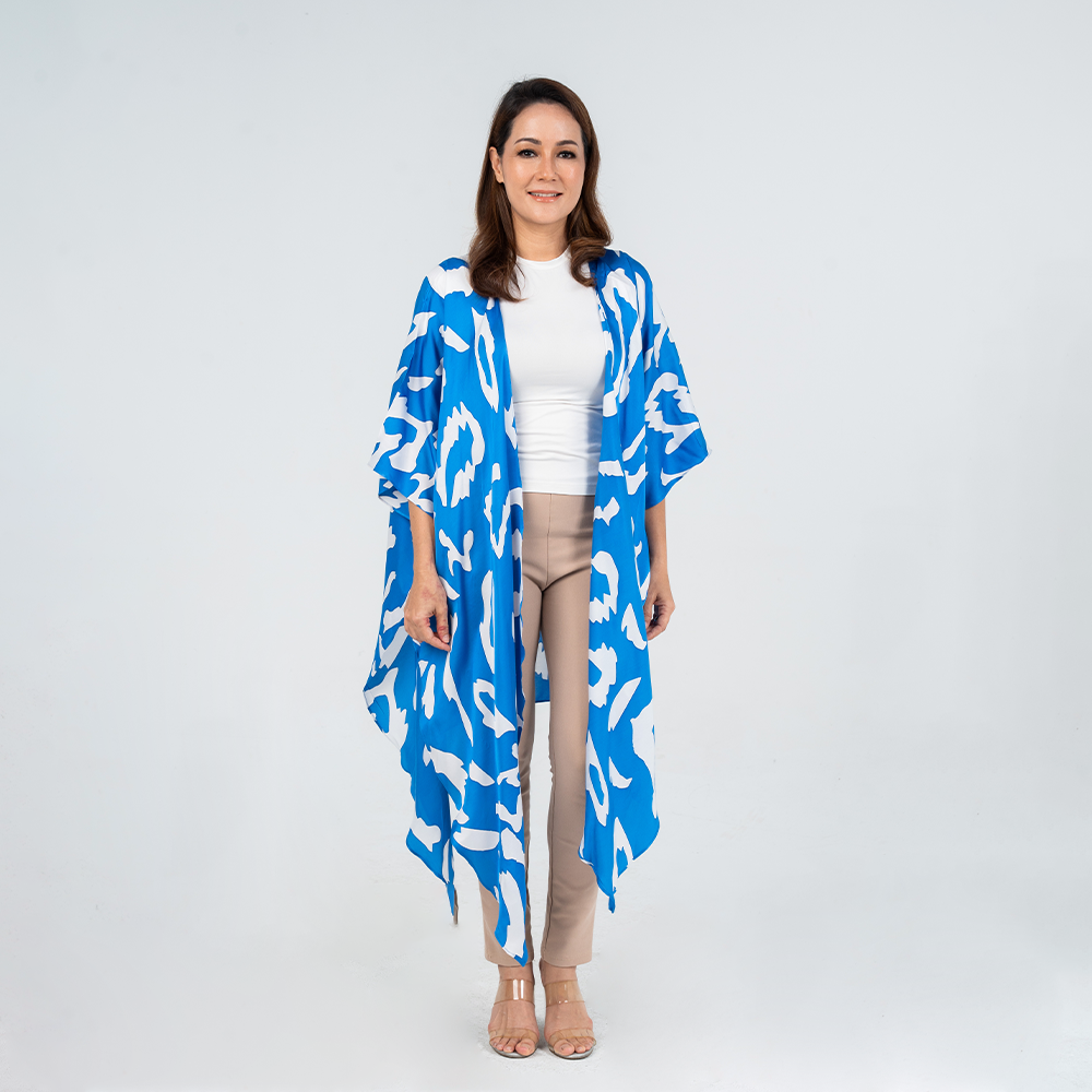 Woman wearing Batik Boutique’s Blue Rimba kimono with bold hand-drawn batik patterns in blue and white, styled over a white top and beige pants