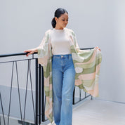 Model wearing Batik Boutique's Moss Bukit batik kimono in an airy lifestyle setting, showcasing its drape and pastel green tones