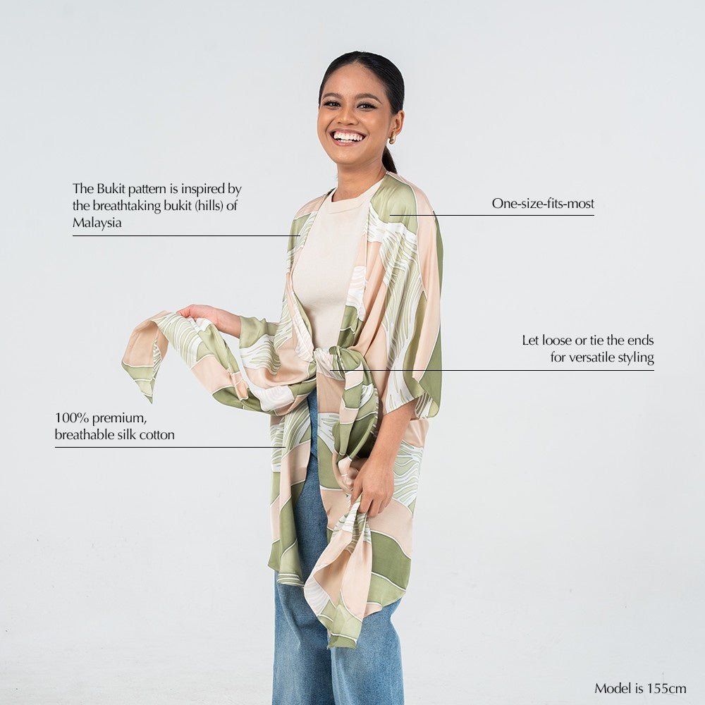 Batik Boutique’s Kimono in Moss Bukit print displayed with callouts showing its silk cotton fabric, versatile styling options, and Malaysian hill-inspired batik design