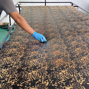 Person applying a patterned material to a large surface with gloves on
