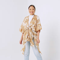 a woman standing in front of white background styling batik long kimono in ultra gold pattern