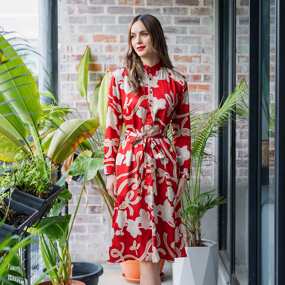 a woman poses in batik long shirt dress in the pattern ruby fleur in a lifestyle photo