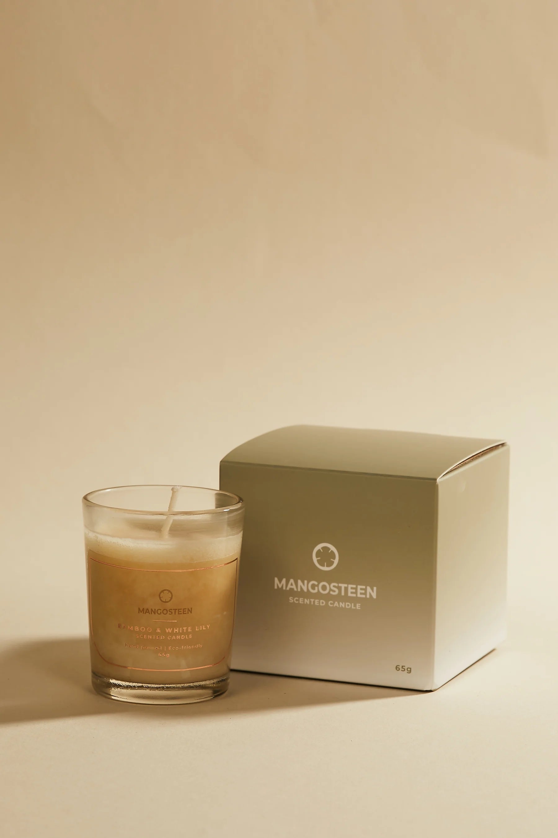 Mangosteen candle in a glass jar with a matching box on a beige background