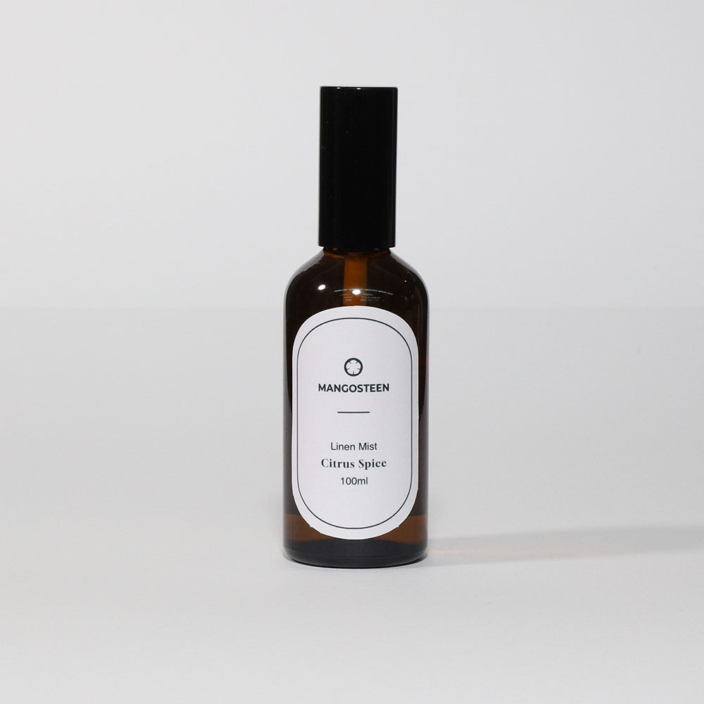 A bottle of Linen Mist - Citrus Spice (Mangosteen) room spray with a white label on a white background.