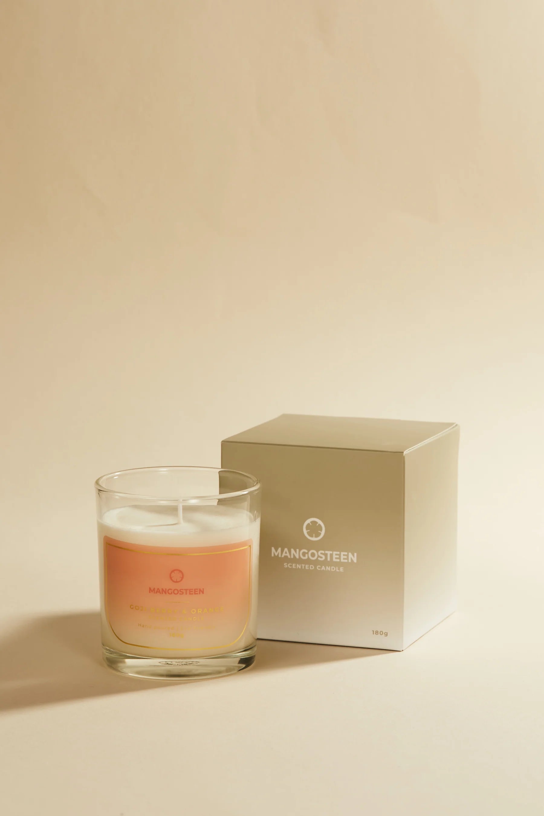 Candle with a 'Mangosteen' box on a beige background