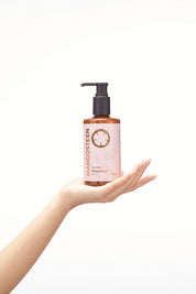 Hand holding a pink bottle labeled 'Mangosteen' against a white background