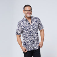 a man posing happily in an authentic batik shirt in the pattern black floret made by malaysian artisans against a neutral background