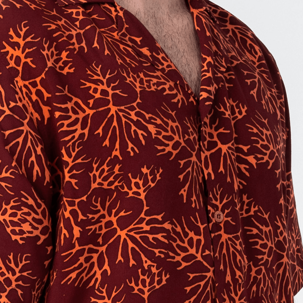 Closeup of maroon coral batik print with wooden button detail.