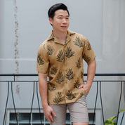 a male model posing in a lifestyle photo wearing a batik cuban in the pattern tan olive leaf 