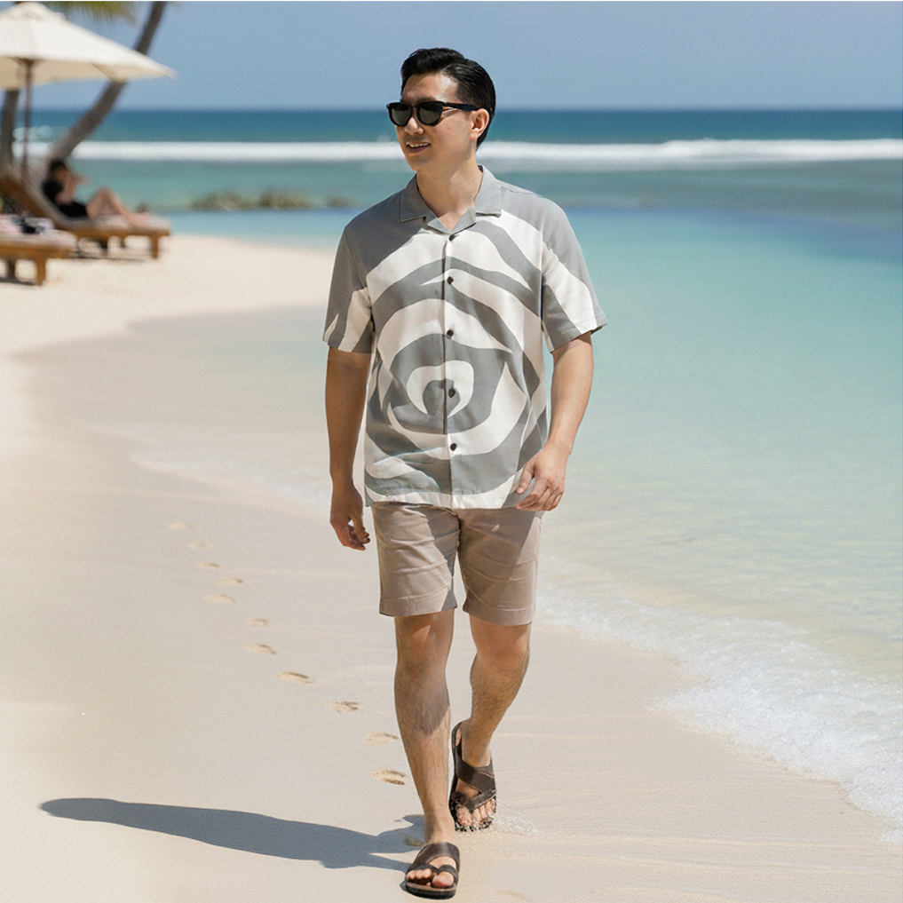 man waking on sandy beach with a silver rose batik boutique shirt