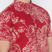 a closeup shot of a man wearing a batik shirt in the pattern crimson orchid