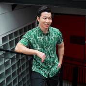 a man posing in a batik shirt in the pattern green tiffin 