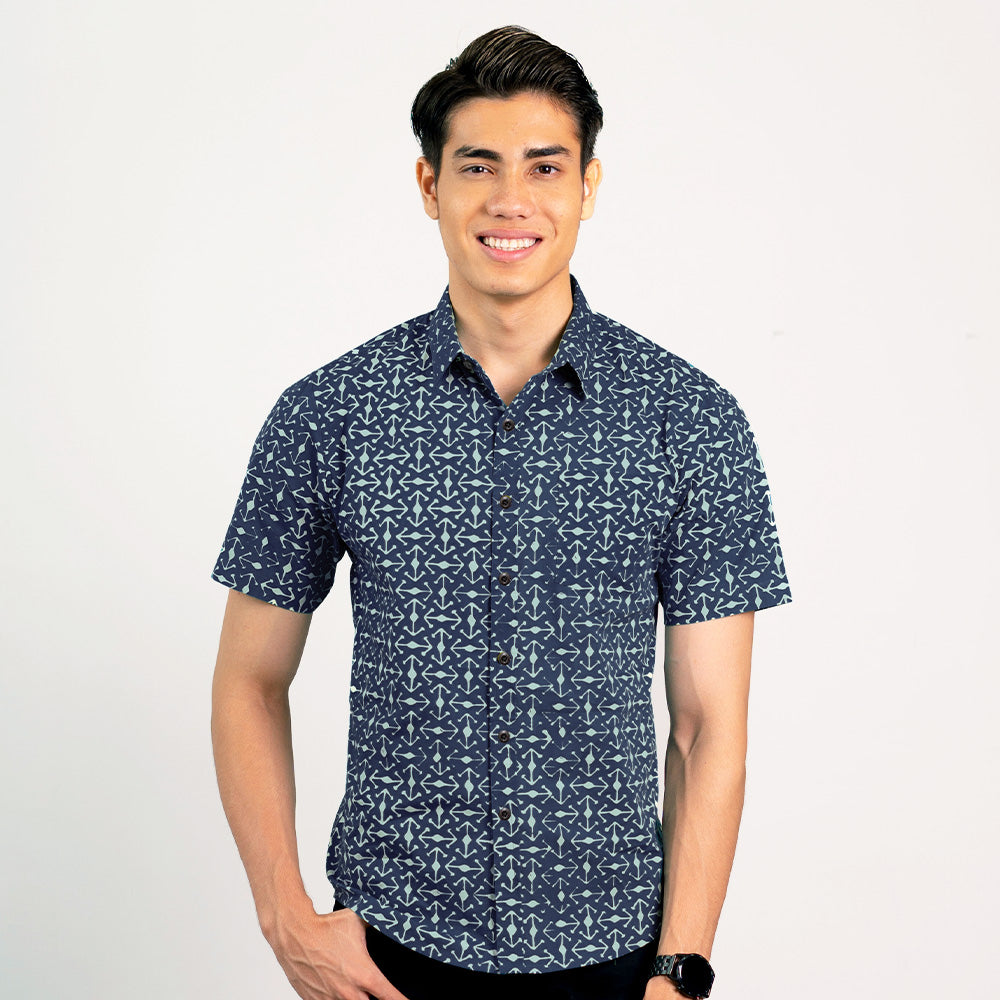 a man standing in front of a white wall while wearing a batik shirt in navy kompas from batik boutique
