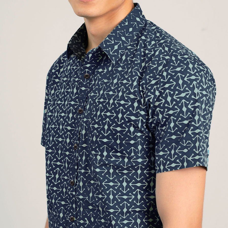 a close up of a man standing in front of a white wall while wearing a batik shirt in navy kompas from batik boutique