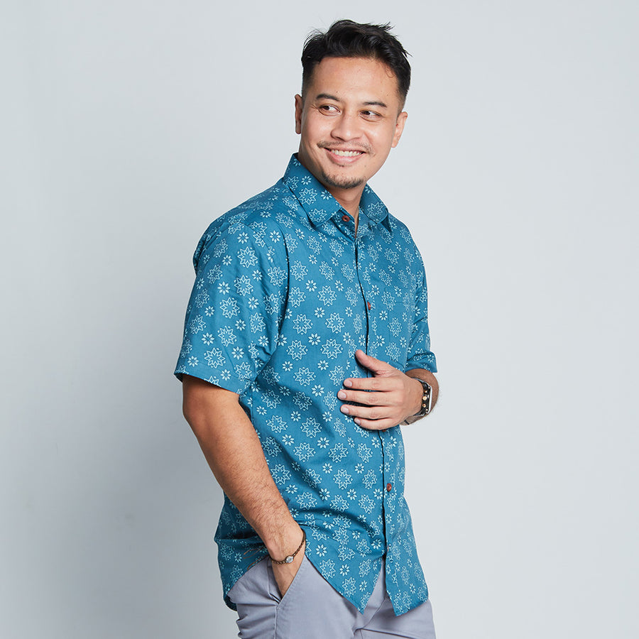 a man standing in front of white background styling batik shirt sleeved in ocean Bintang pattern  