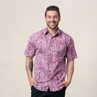A man striking a confident pose against a neutral background, showcasing the authenticity of his batik shirt in the elegant Pink Floret pattern