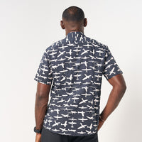 photo of man standing in front of white background wearing batik shirt in black colour and pattern inspired from airplane