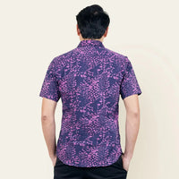 A rear view shot, accentuating the detailed design of a man's authentic Purple Bintik patterned batik shirt, set against a neutral background