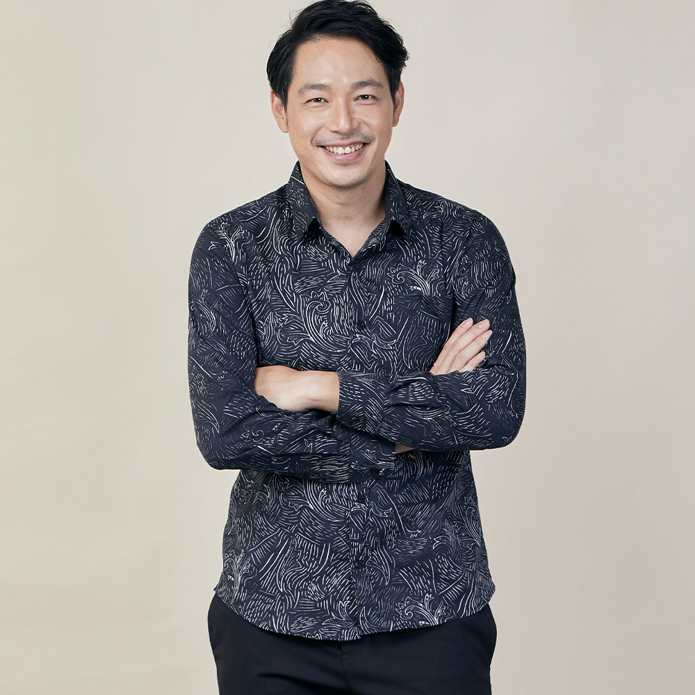 A white box style photo featuring a gentleman confidently posing in a Driftwood patterned batik shirt against a neutral background