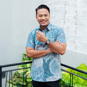 Man wearing the Slate Petola batik shirt, smiling confidently in an outdoor setting