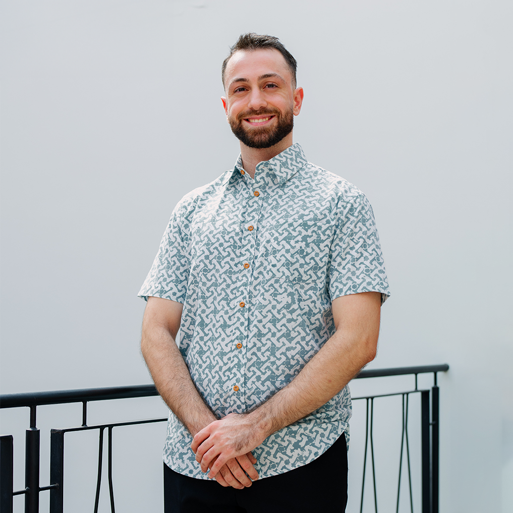 Man wearing teal Arabesque batik shirt in outdoor setting.