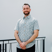 Man wearing teal Arabesque batik shirt in outdoor setting.
