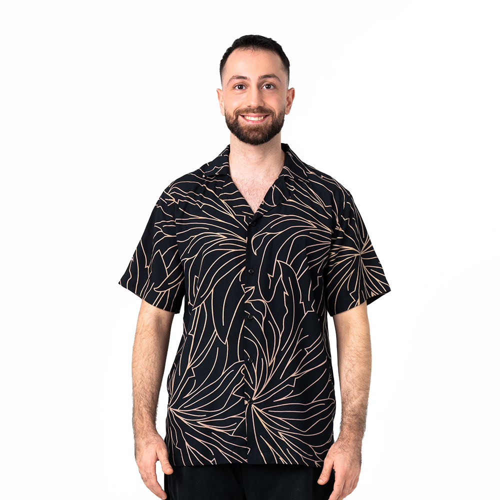 Model wearing men’s Onyx Palma Cuban shirt with bold Southeast Asian batik leaf design.