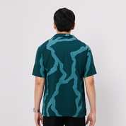Person wearing a green and blue patterned shirt on a white background