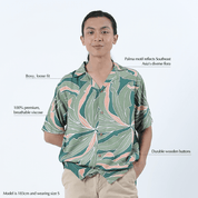 Man wearing a green and pink leaf pattern shirt on a white background