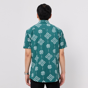 Person wearing a green patterned shirt on a plain background