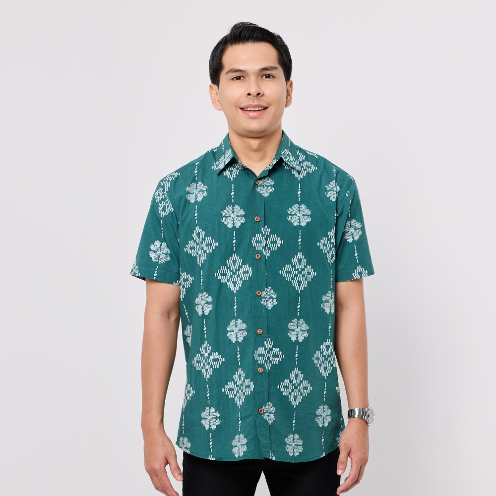 Man wearing a green patterned shirt on a plain background