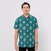 Man wearing a green patterned shirt on a plain background