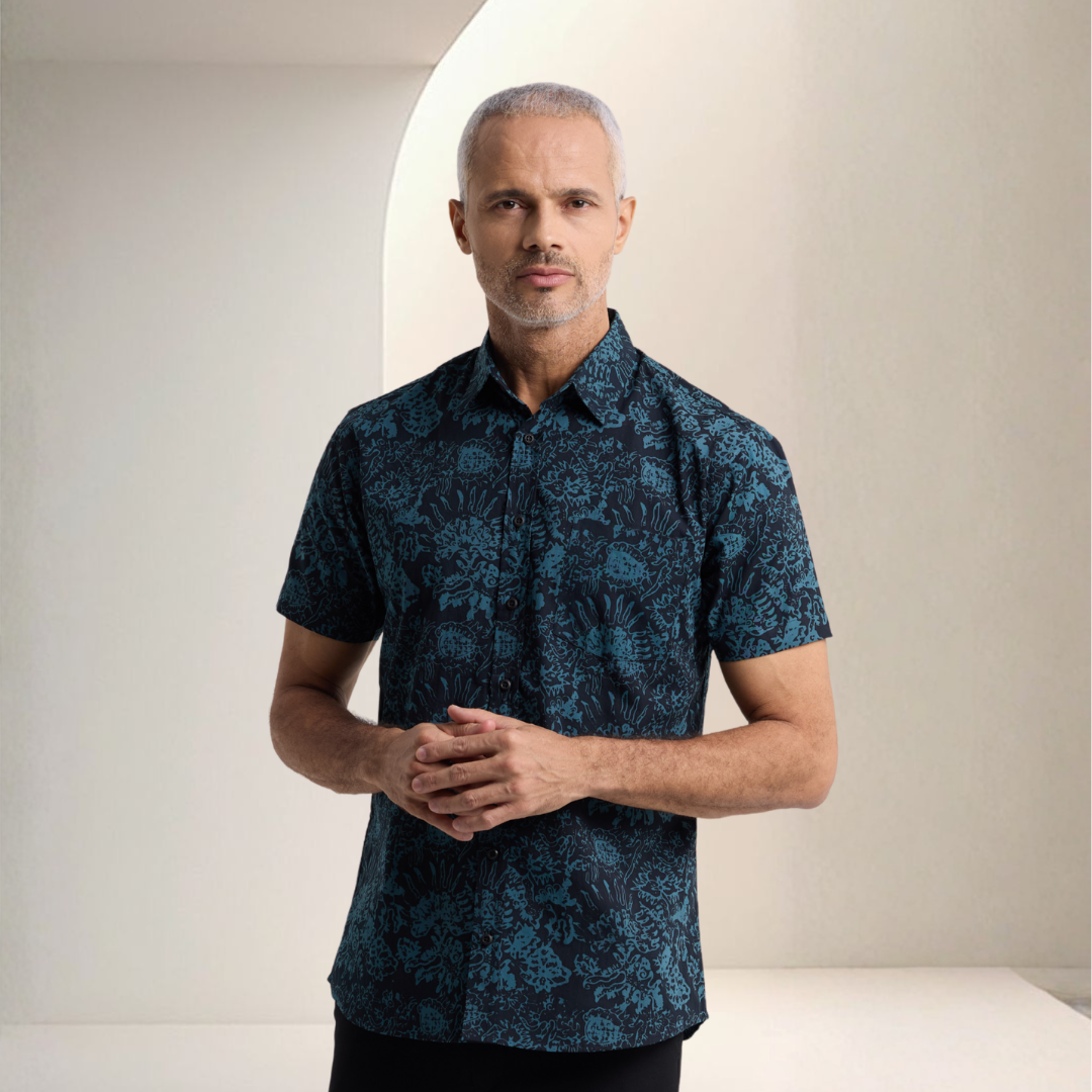 Man wearing a dark blue patterned shirt against a neutral background