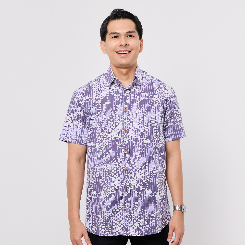Man wearing a purple and white patterned Batik shirt on a plain background