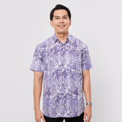 Man wearing a purple and white patterned Batik shirt on a plain background