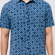 Blue patterned shirt worn by a person on a plain background