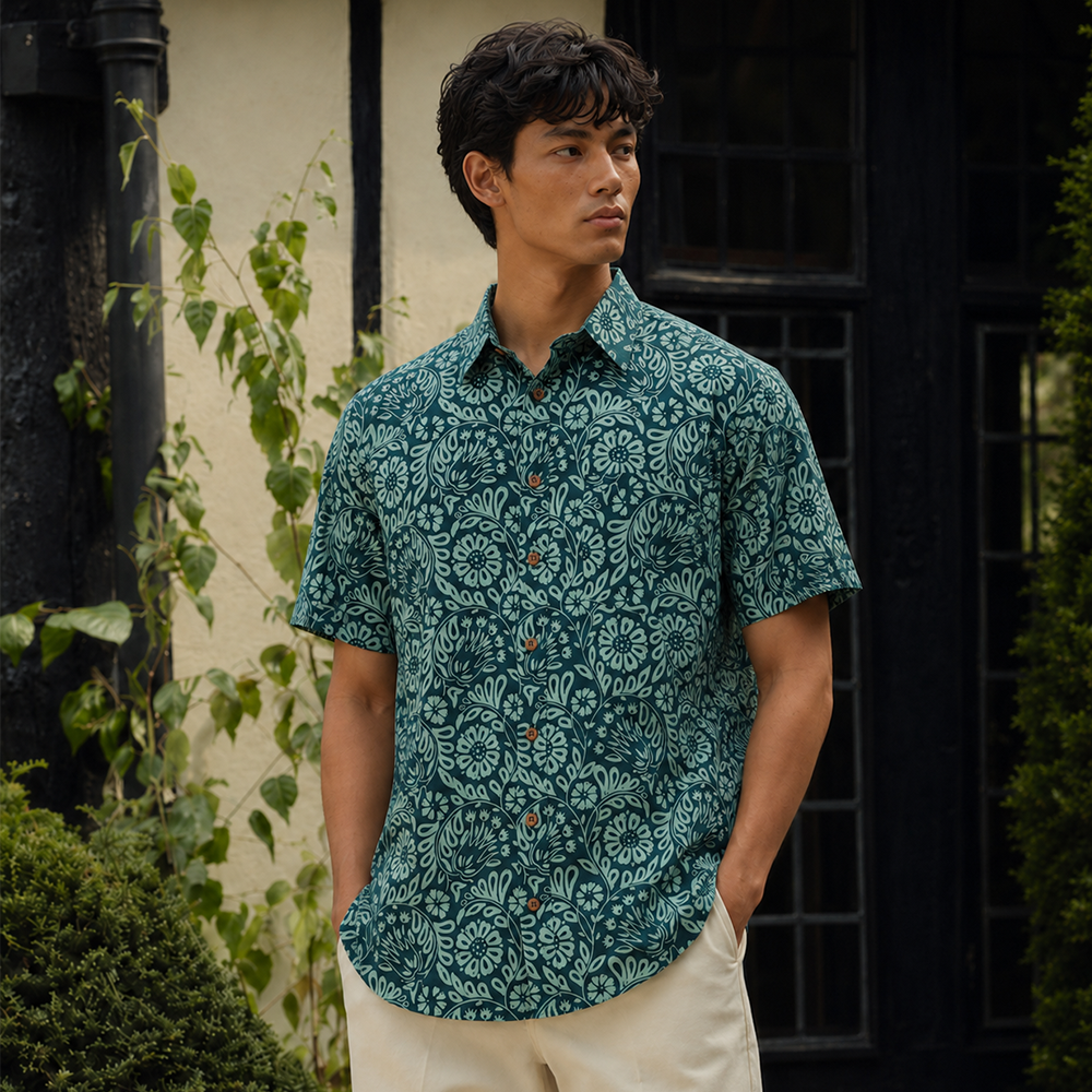 Man wearing teal printed batik shirt, posing outdoors with his hands in his pockets