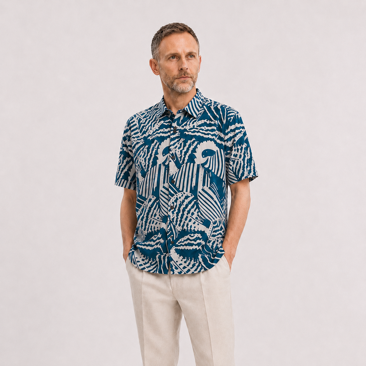 A man wearing a blue button-up shirt with a blue shell pattern, on a white background.