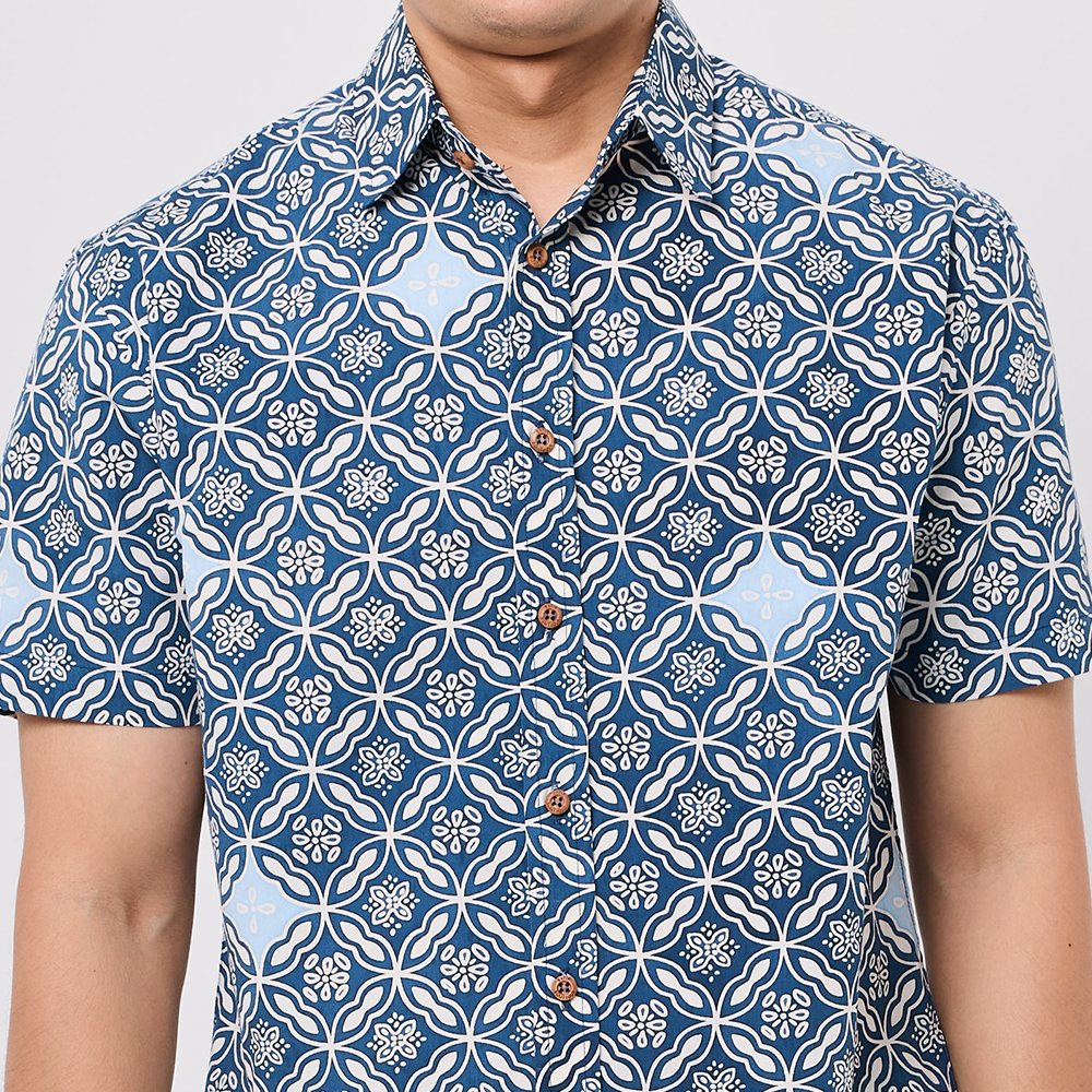 Person wearing a blue and white patterned shirt on a plain background