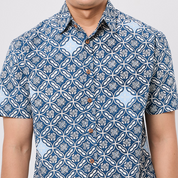 Person wearing a blue and white patterned shirt on a plain background